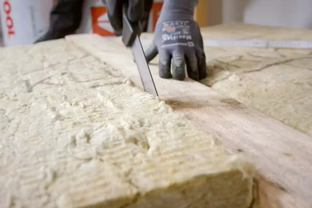 Eine Person schneidet einen Dämmstoff von ROCKWOOL zu